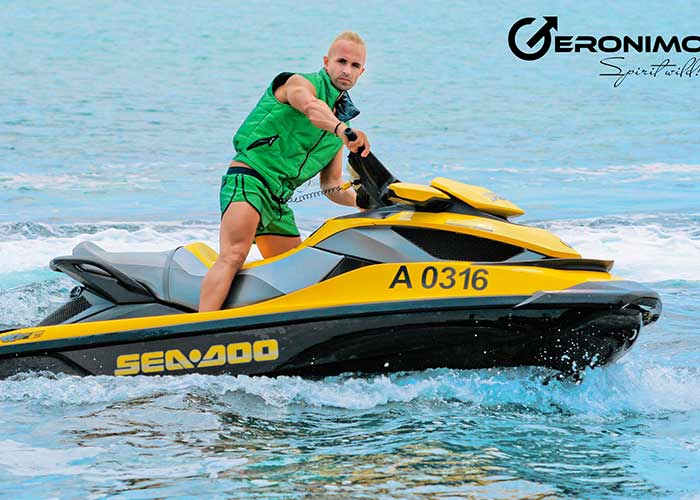 fotografiya-sportivnyj-nakachennyj-muzhchina-zelenyh-plavkah-i-v-zhiletke-na-more-okeane-kataetsya-na-vodnom-motocikle.jpg